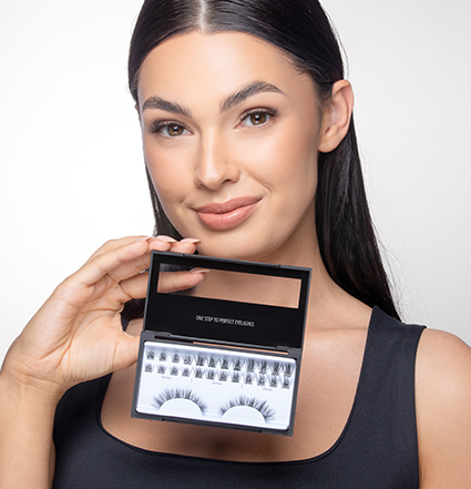 A woman with black hair smiling and holding a lash extension set