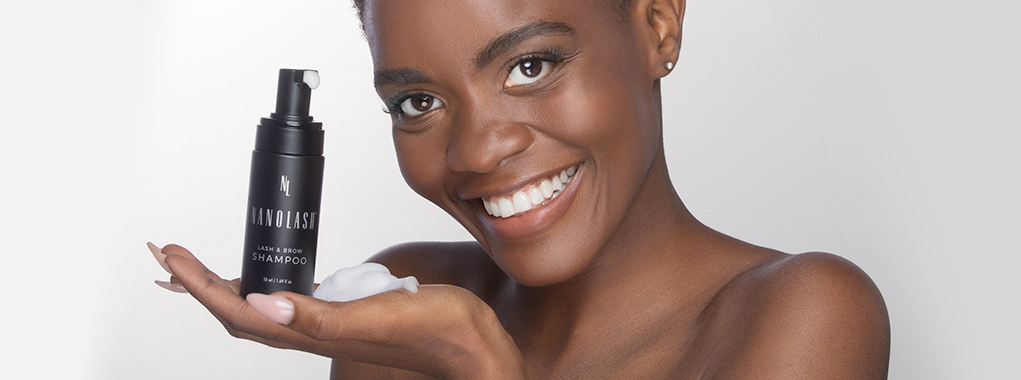 Black woman holding a Lash and Brow Shampoo in her hand